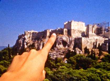 a ponit of view shot of a finger pointing at a historical building