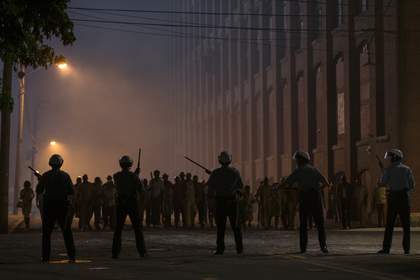 film still of police standing in a city protecting against a riot