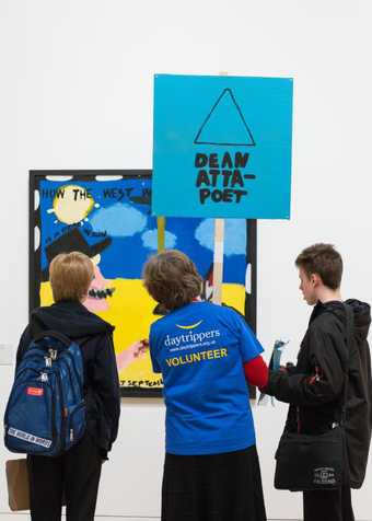 Two children holding a placard in the gallery in front of an abstract painting