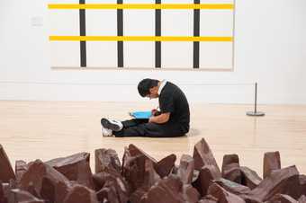 A child sits on the floor in front of a Richard Long installation and an abstract grid painting