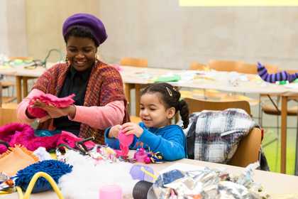 An artist and young girl craft with bright pink fabric in Tate Britain