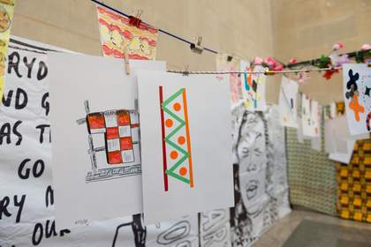 Painted posters and paper works hang up in the gallery like a washing line