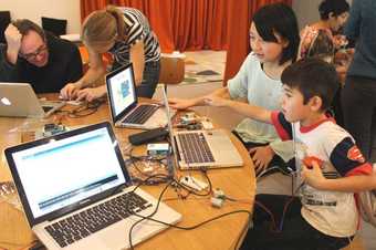 children sit on a table next to a laptop