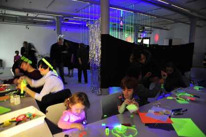 Black fabric hanging in background and kids and adults making shapes in the foreground