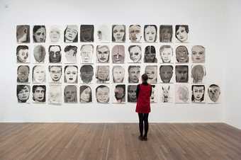 Women in a red dress viewing Marlene Dumas: Image as Burden exhibition artwork