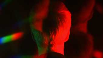 Ed Atkins Death Mask II: The Scent, a red coloured photograph or film still of a the back of a man's head