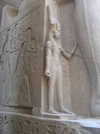 Statue of the great royal wife Nefertari, at the side of a colossal enthroned statue of Ramses II, temple of Luxor, 19th dynasty