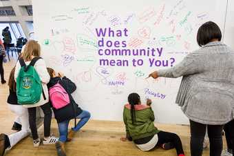 A group of people look at text that says 'what does community mean to you?'