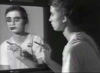 Still from Video Art black and white image of girl in front of a mirror with paint over her eye.