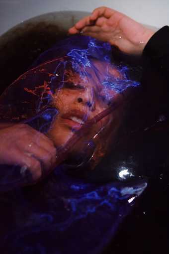Photo of woman lying in bath with netting over her face