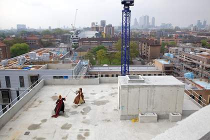 Two people have a fight on top of a building