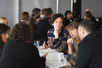 A group of people are in discussion and taking notes
