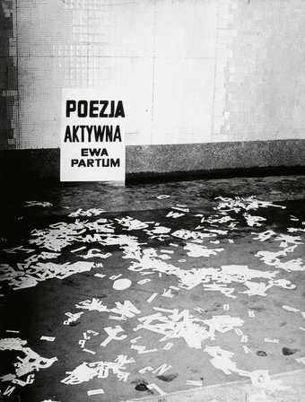 Ewa Partum Active Poetry 1971 photograph of a performance there are white paper letters of the alphabet strewn across the floor