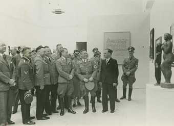 Exhibition co ordinator Hartmut Pistauer leads Nazi party officials through the Degenerate Art Exhibition at the Kunst Palast in Dusseldorf 1938 photograph of men in uniforms looking at art 