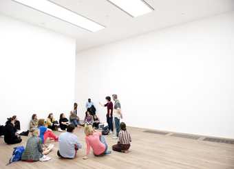 Group sitting on the floor in a white walled gallery space