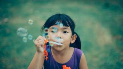 Photograph of a young girl blowing bubbles