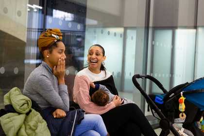 Young mother breastfeeding next to her friend in tate modern