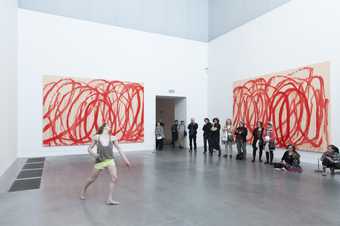 A male dancer dances in a Tate Modern gallery space with visitors watching
