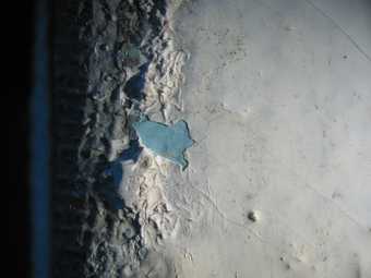 Detail of loss in white paint revealing turquoise underneath