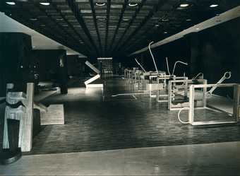 Black-and-white photograph of a large exhibition hall, with Roberto Chabet’s Hurdling 1970, a series of vertically suspended frames (a reference to athletic hurdles) from which stem jagged protrusions made of found scraps of metal