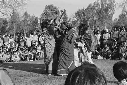 A group of figures stand together holding a rope above their heads, while a crowd looks on.