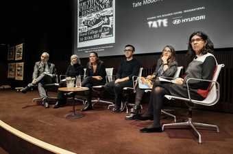 Photo of the six-person panel onstage at Tate Modern, all appearing to listen to a member of the audience speaking