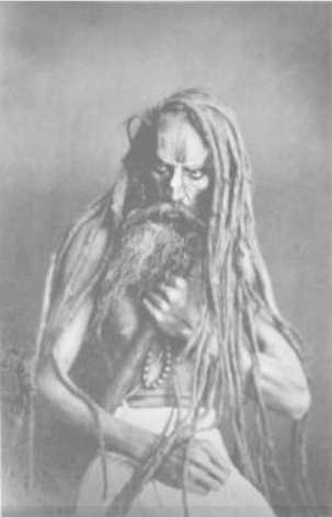 A portrait of a figure with long hair and a long beard, grasping a pole-like object and some beads against their chest.