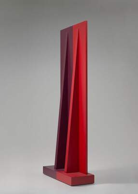 Photograph of a red geometric sculpture; two slender triangles support a larger vertical rectangle, all sitting on a thick rectangular base