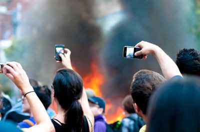 ‘A crowd of spectators using their mobile phones to capture footage of a burning police car on Queen St. W. in Toronto during the 2010 G20.’