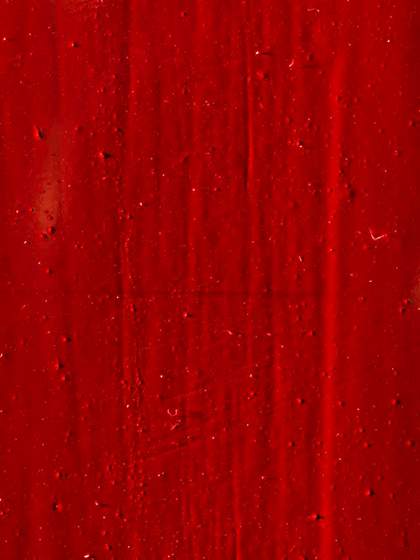 A detail of the deep red surface of Red Barn Door showing small solid flecks and vertical and horizontal scratches and marks.