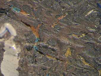 Micrograph of area between red and blue planes showing brown, yellow and blue paint beneath