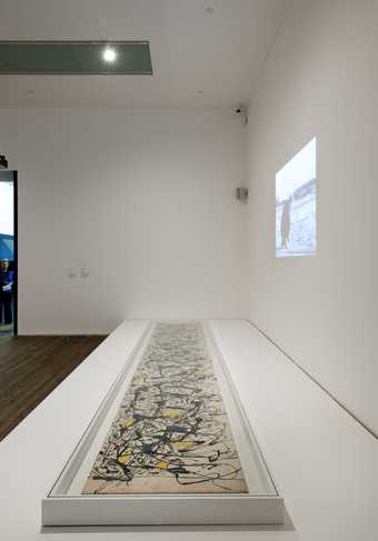 Fig.2 Installation view of Jackson Pollock’s Summertime: Number 9A with footage of Hans Namuth’s film playing above in A Bigger Splash 2012