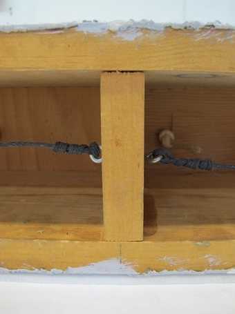 A close-up view showing two horizontal pieces of wood connected by a vertical one, with a vertical pencil line drawn above the central point of the vertical piece of wood.