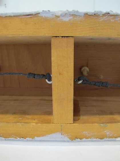 A close-up view showing two horizontal pieces of wood connected by a vertical one, with a vertical pencil line drawn above the central point of the vertical piece of wood.