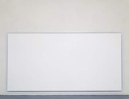 A photograph of a large white canvas hanging just off the floor in a gallery space.