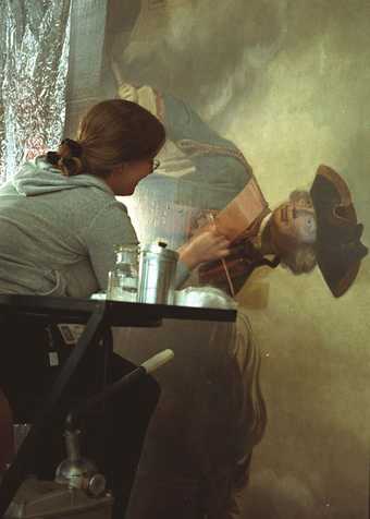 A conservator removing varnish from a painting