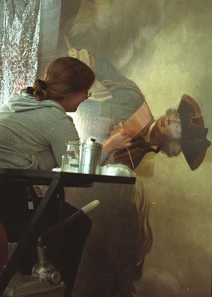 A conservator removing varnish from a painting