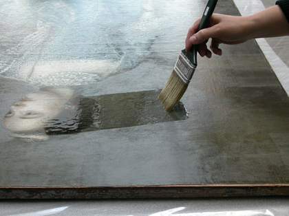 A large paint brush being used to add varnish to a painting
