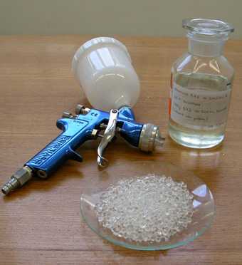 An image showing a plate of translucent crystals, a bottle of acid and a spray gun for application