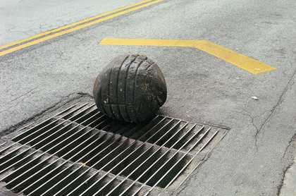 Gabriel Orozco Yielding Stone 1992 colour photograph of the road and grate with a peice black ball of plastercine with the imprint of the grate