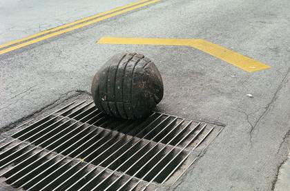 Gabriel Orozco Yielding Stone 1992 colour photograph of the road and grate with a peice black ball of plastercine with the imprint of the grate 
