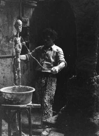 Giacometti working with plaster in his Paris studio in 1959, photographed by Isaku Yanaihara