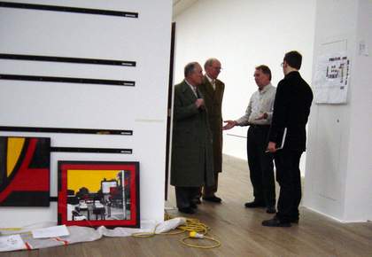 Gilbert and George next to hanging rails for a photo piece