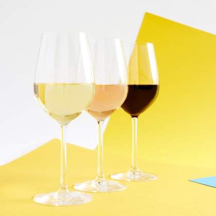 Photograph of three full wine glasses showing the house range of rose, white and red.