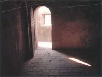 Film still of an open door in a run down stone building