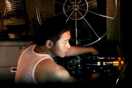 A projectionist and a film projector; a young woman sweeping an empty cinema