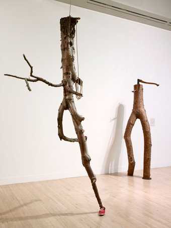 Goshka Macuga Objects in Relation 2007 tree trunks and branches arranged so that they look like two figures moving one with a red trainers on