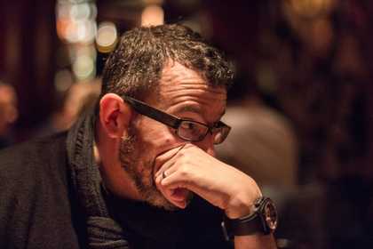 man with glasses holding chin in hand