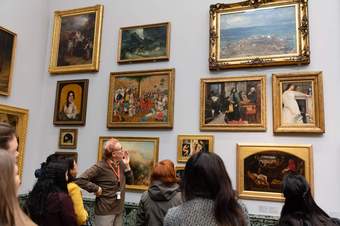 A member of Tate staff talks to a group of visitors in front of a painting at Tate Britain.