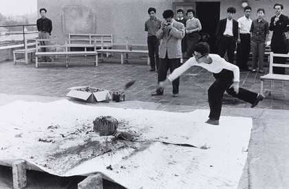 Otsuji Kiyoji documents Shimamoto Shōzō throwing glass bottles of colourful pigments against a stone at the centre of a canvas, 2nd Gutai Exhibition, Tokyo, 1956